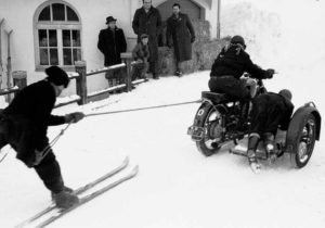 Vintage photo of skijoring skier pulled by motorbike with sidecar | Writer Mariecor | WriterMariecor.com